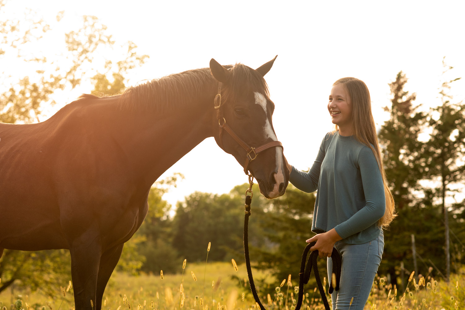 Isabella smiling and petting her horse on the nose