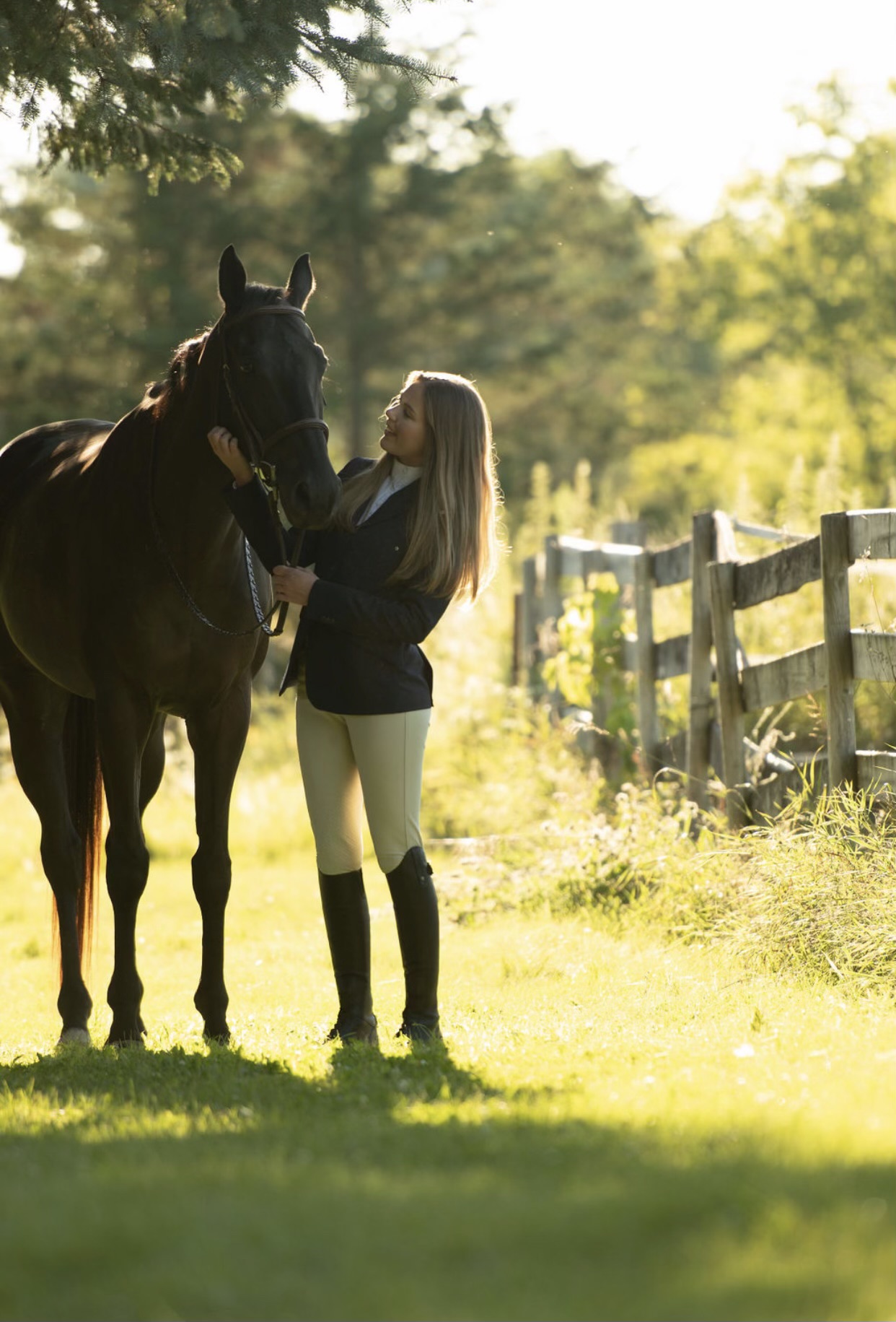 Cheerful young woman holding a Thoroughbred horse by the bridle